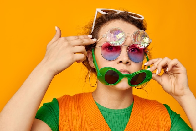 Vrolijke vrouw oranje sweatshirts zonnebril veelkleurige glazen leveren gele achtergrond ongewijzigd