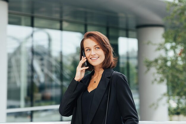 Vrolijke vrouwelijke ondernemer die op een mobiele telefoon praat