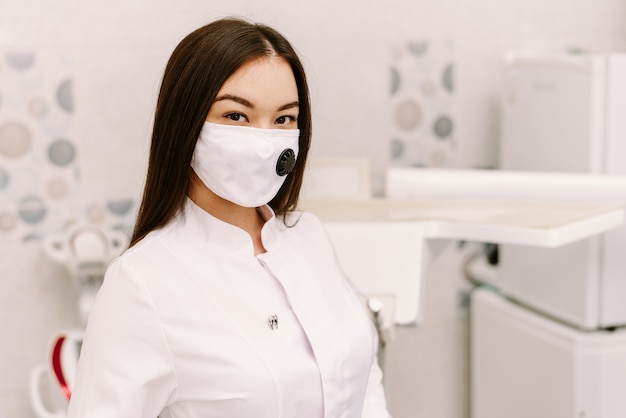 Vrolijke vrouwelijke tandarts die op haar kantoor glimlachen