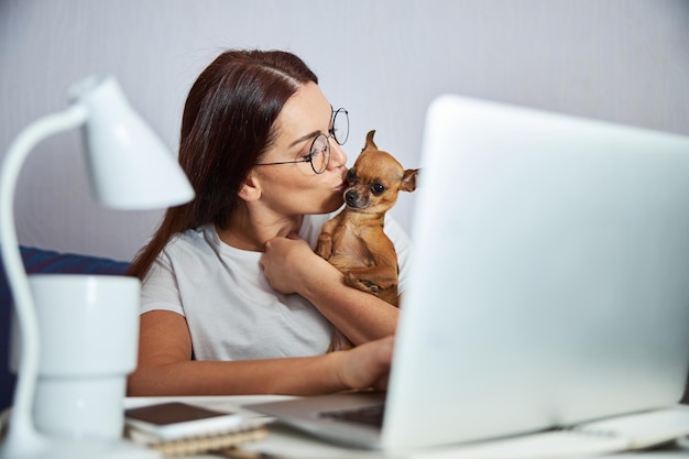 Vrolijke vrouwelijke zoenende hond tijdens het werken op laptop