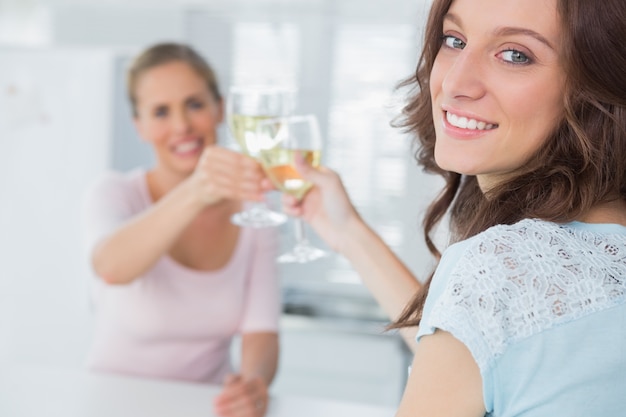 Vrolijke vrouwen die glazen witte wijn houden