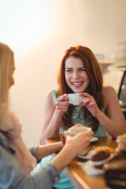 Vrolijke vrouwen sprekende vriend bij koffiewinkel