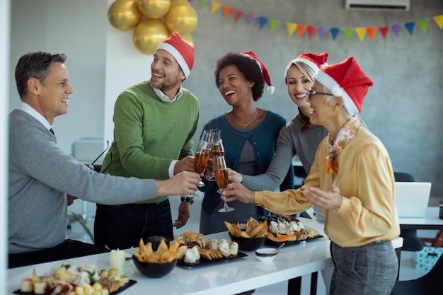 Vrolijke zakencollega's proeven met champagne op nieuwjaarsfeest op kantoor