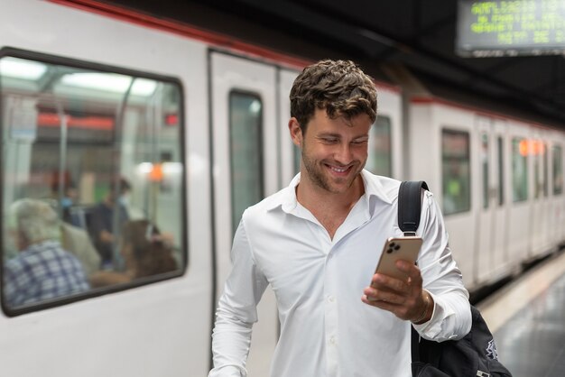 Vrolijke zakenman die smartphone op station gebruikt