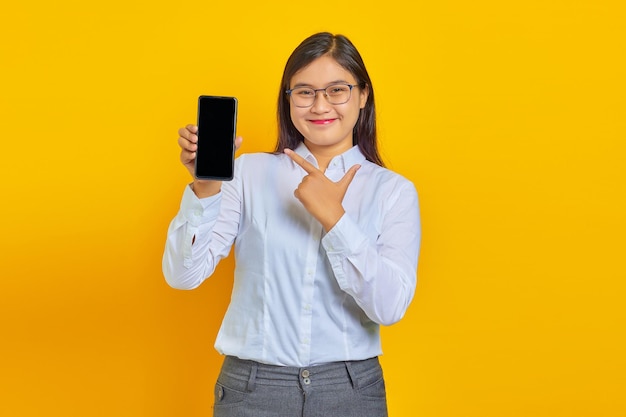 Vrolijke zakenvrouw die een leeg smartphonescherm toont en ernaar wijst terwijl ze naar de camera kijkt