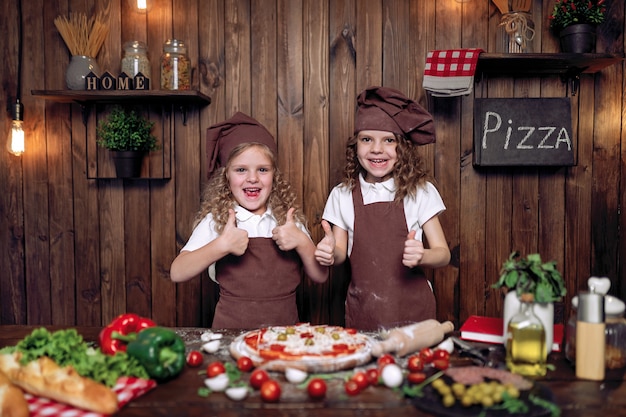 Vrolijke zusters die pizza samen koken