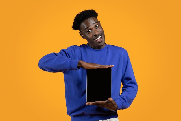 Vrolijke zwarte man die digitale tablet met een leeg scherm laat zien