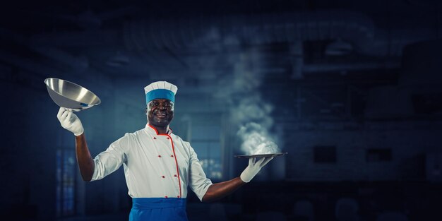 Vrolijke zwarte man met een schort en koken in actie. Gemengde media