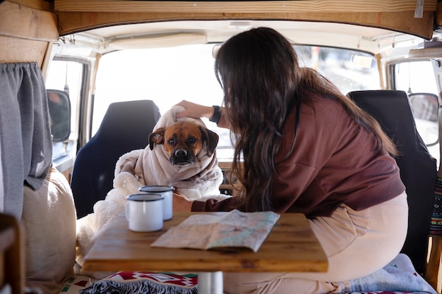 Foto vrouw aait haar boxer in een camper tijdens wintertrip