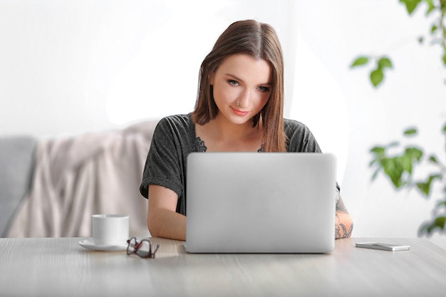 Vrouw aan de tafel zitten en werken met laptop