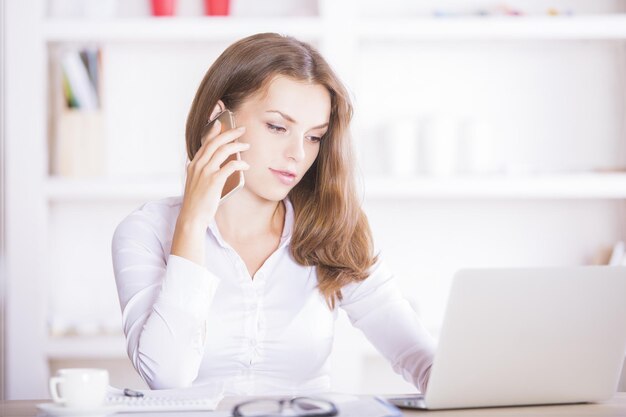 Vrouw aan de telefoon met behulp van laptop