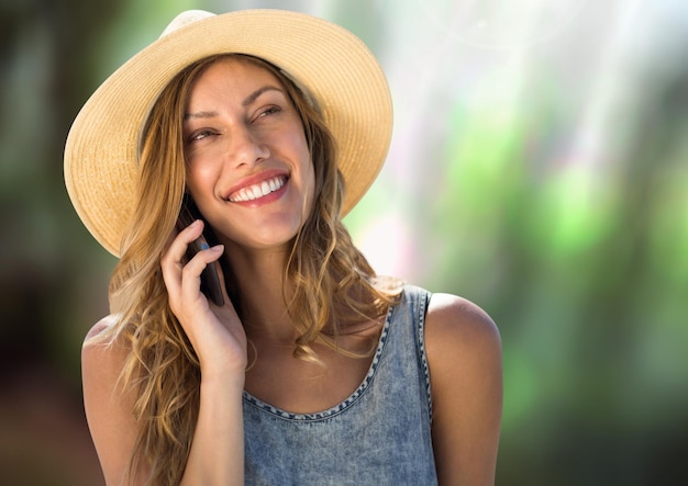 Vrouw aan de telefoon met hoed in het bos