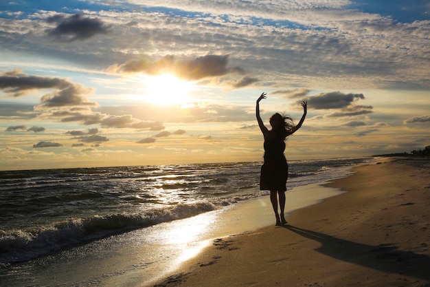 Vrouw aan de zeekust bij zonsondergang