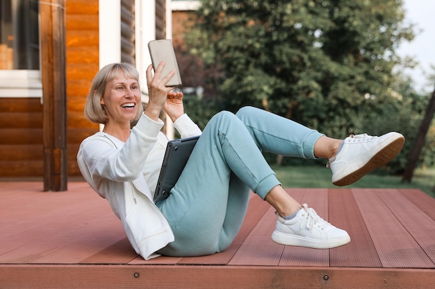 Vrouw aan het werk in park met telefoon en laptop Zakenvrouw werkt buiten groene natuur achtergrond Wi-fi netwerkverbinding gratis toegang Freelancer ontspannen in de natuur en het gebruik van technologie