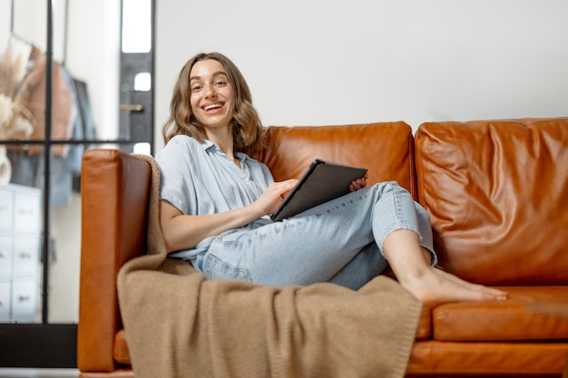 Vrouw aan het werk met digitale tablet vanuit huis op de bank