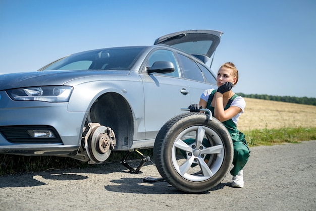 Foto vrouw aan het werk met gebroken wiel van haar auto, wachtend op hulp