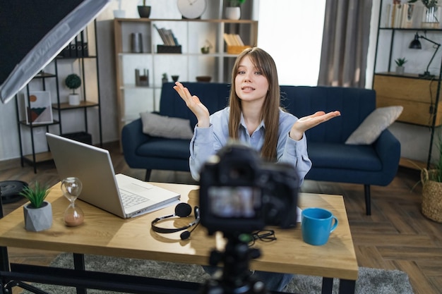 Vrouw aan tafel zitten met laptop en video opnemen