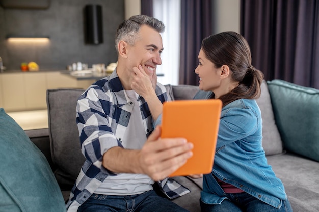 Vrouw aanraken van het gezicht van de echtgenoot met tablet