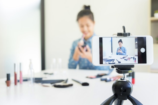 Vrouw aanwezig schoonheidsproduct en uitzend live video naar sociaal netwerk via internet thuis, schoonheid blogger concept.