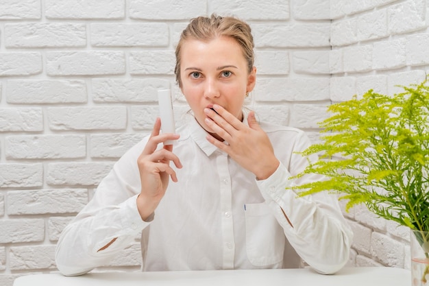 Vrouw adviseert u cosmetisch product met witte bakstenen muur achtergrond Cosmetica schoonheid en spa concept