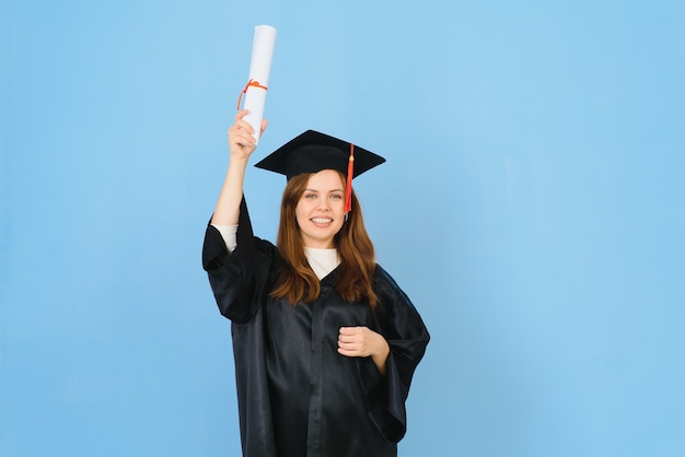 Vrouw afgestudeerde student met afstuderen hoed en jurk, op blauwe achtergrond