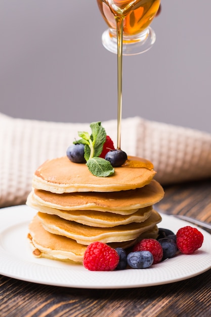 Vrouw ahornsiroop gieten op lekkere pannenkoeken.