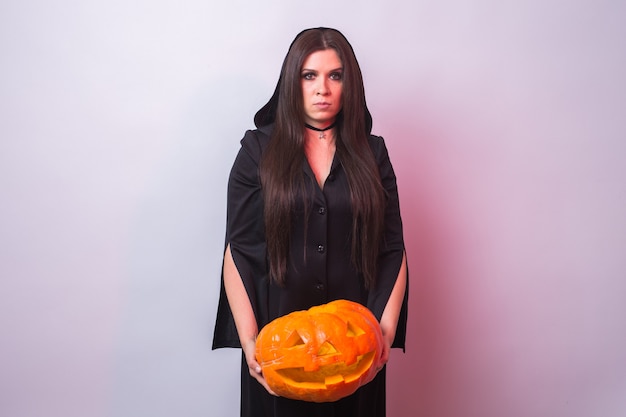 Vrouw als heks staat met het pompoen Halloween en carnaval concept.