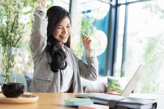 vrouw armen omhoog en met behulp van laptop en smartphone online winkelen website