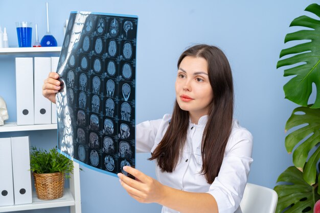 Vrouw arts die MR van de patiënt beeld in haar bureau onderzoeken