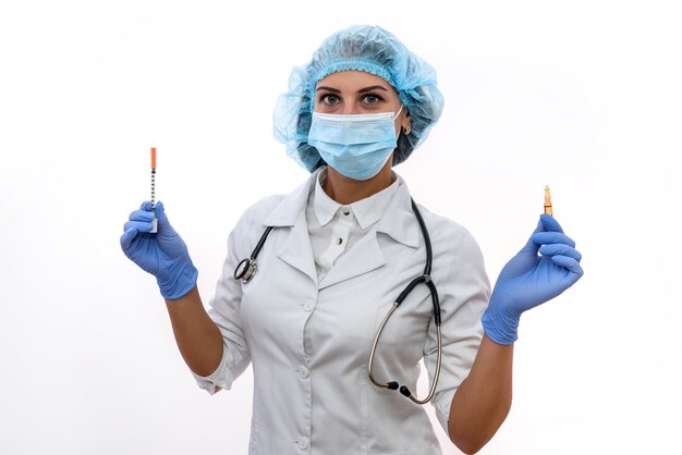 Vrouw arts in beschermend masker en handschoenen met spuit en ampul geïsoleerd op wit