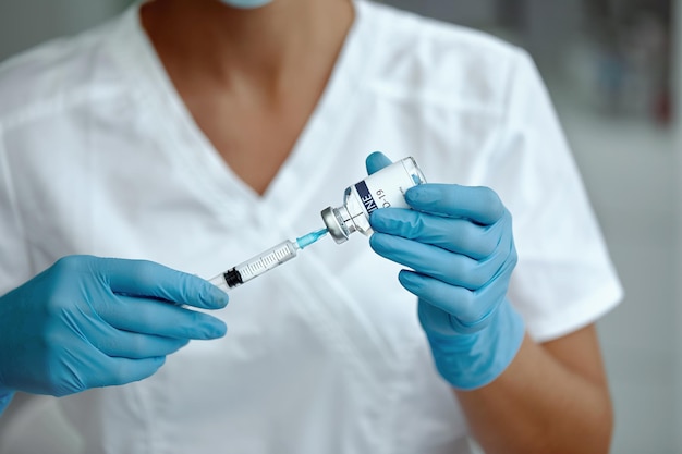 Vrouw arts of wetenschapper in laboratorium met een spuit met vaccins. vrouw met covid-19-vaccin in de hand. concept: ziekten, medische zorg, wetenschap.