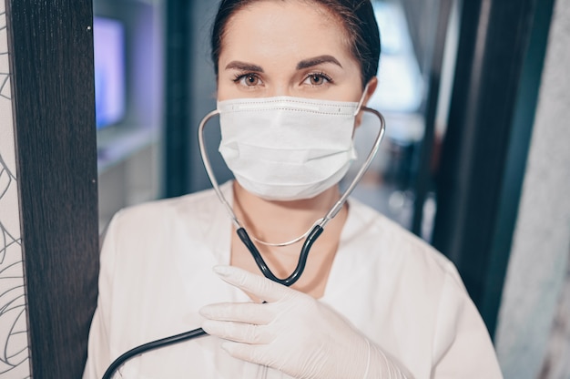 Vrouw arts verpleegster die beschermend masker en stethoscoop draagt voor controle ademhaling, coronaviruspreventie, hygiëne om het verspreiden van coronavirus te stoppen. Voorkom besmetting van het Corona virus Covid-19 concept