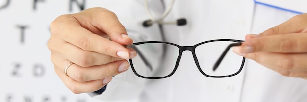 Vrouw artsen handen houden nieuwe stijlvolle bril in optica close-up selectie van brillen om te werken