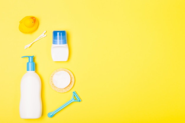 Vrouw bad schoonmaak zorg ochtend routine bovenaanzicht plat lag samenstelling met witte, blauwe gele items op geel bureau.