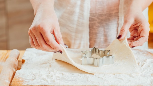 Vrouw bakken Handen die koekjes maken met behulp van koekjessnijder om plat gebakdeeg close-up uit te snijden Keuken spullen gereedschap gebruiksvoorwerpen