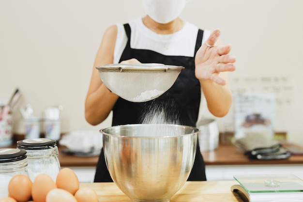 Vrouw bakker bloem zeven in mengkom