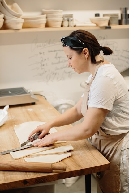 Vrouw bakker snijdt het deeg in driehoeken voor croissants Croissants maken in de bakkerij