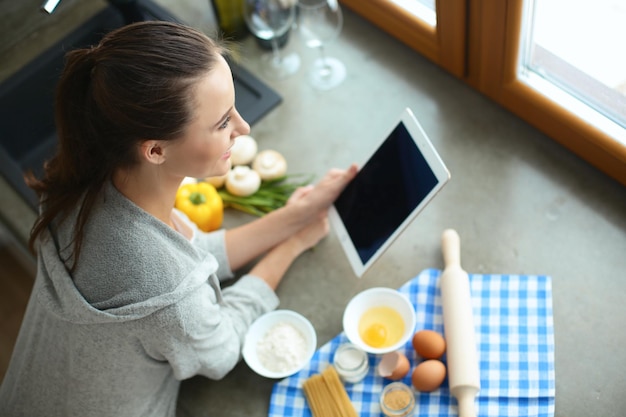 Vrouw bakt thuis volgens recept op een tablet