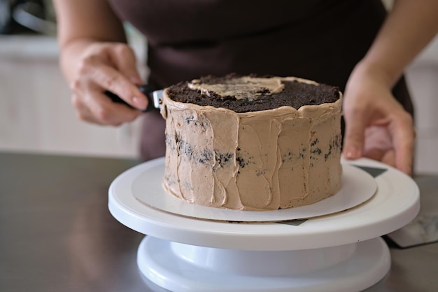 Vrouw banketbakker chocoladetaart maken met chocolade crème close-up Taart maken proces Selectieve focus