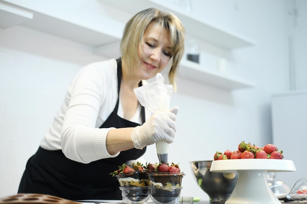 Foto vrouw banketbakker dessert versieren met slagroom met spuitzak horizontale foto