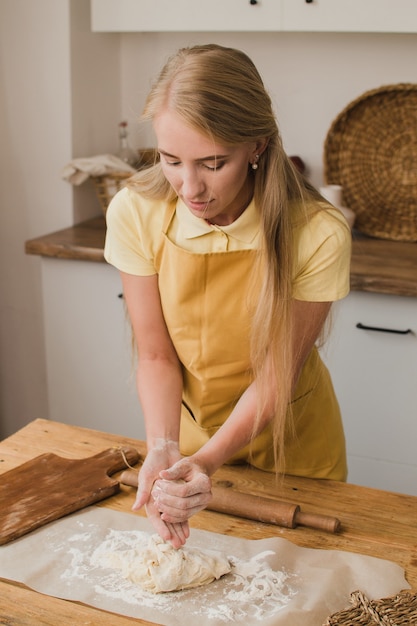 Vrouw banketbakker of bakker of huisvrouw kneedt deeg in de keuken. Reclame voor zelfgebakken producten