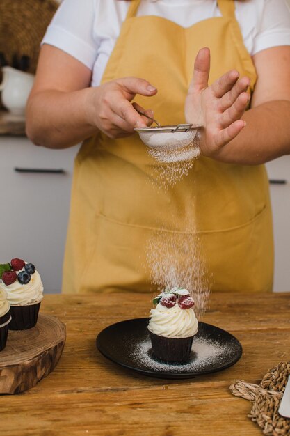 Vrouw banketbakker siert dessert. Zoetwaren of kookcursussen concept