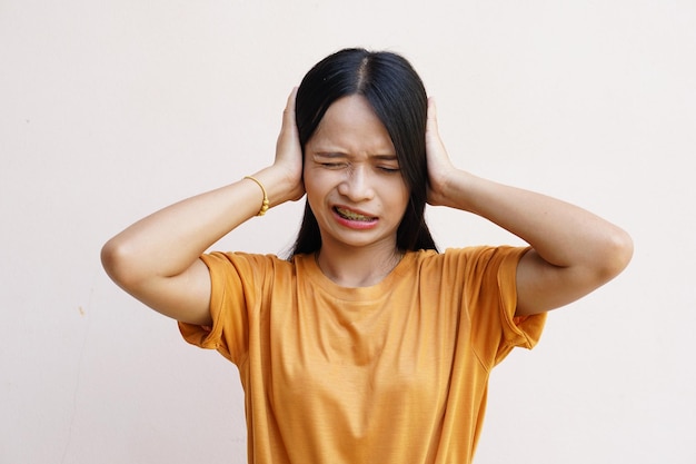 vrouw bedekte zijn oren over grijze achtergrond