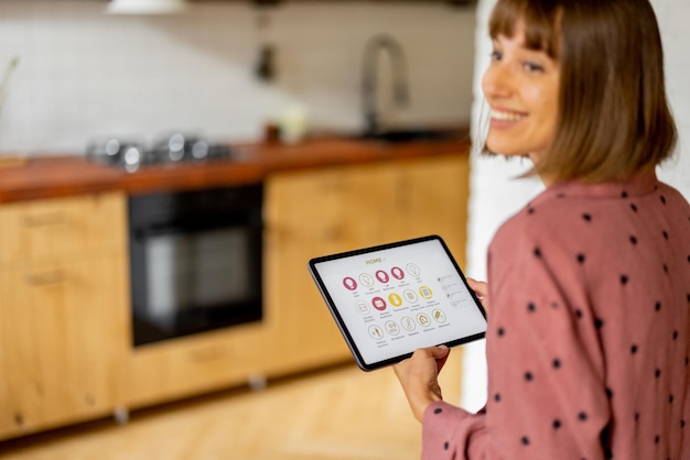 Vrouw bedient thuisapparaten met een digitale tablet thuis