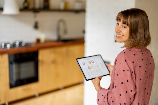 Vrouw bedient thuisapparaten met een digitale tablet thuis