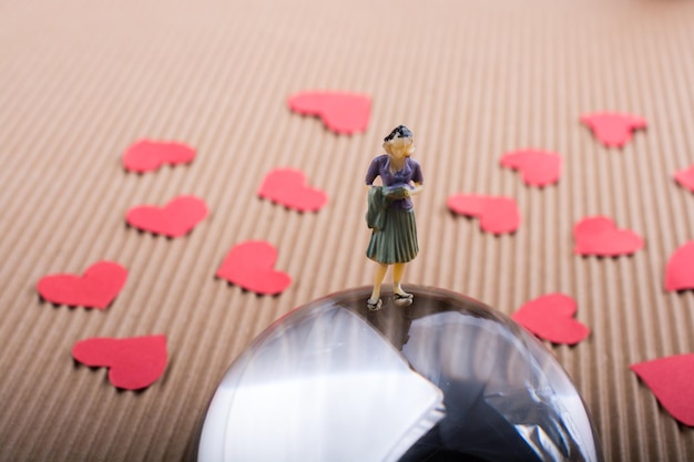 Vrouw beeldje op een halve aardbol met papieren harten
