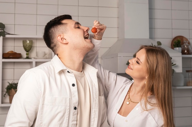 Vrouw behandelt voedende man vrouw die cherrytomaat in de mond van de man stopt, liefdespaar dat plezier heeft bij hom