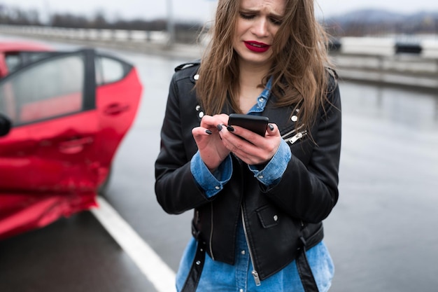 Vrouw belt naar een dienst die bij een rode auto staat