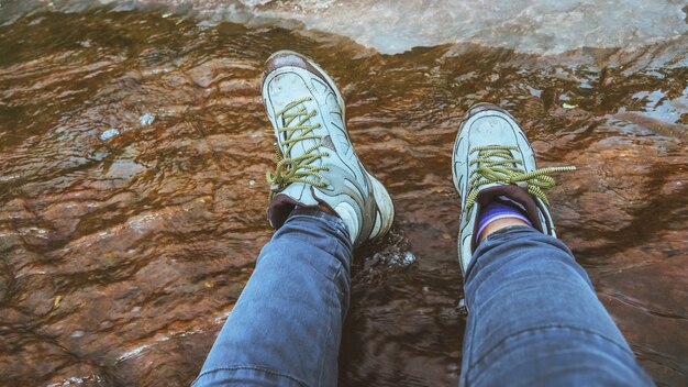 Vrouw benen draagt ​​schoenen lopen in het bos water waden