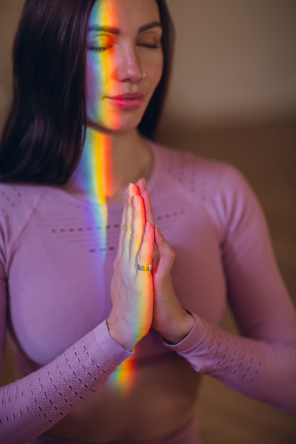 Vrouw beoefenen van meditatie en yoga met regenbooglicht op haar lichaam en gezicht